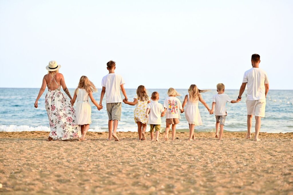 Große Familie geht Hand in Hand am Strand zum Meer – Bild für sicherer Ort und Bindung